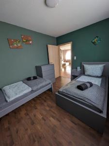 two beds in a room with green walls and wooden floors at FeWo Lorenz in Buchen