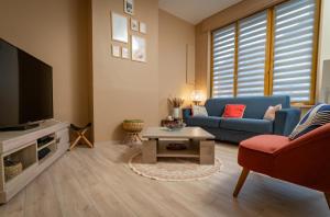 a living room with a blue couch and a tv at Le Jardin Secret in Saint-Omer