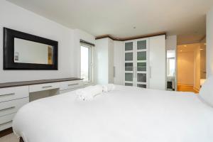 a white bedroom with a large white bed and a television at Borough Flat with City Views by UnderTheDoormat in London