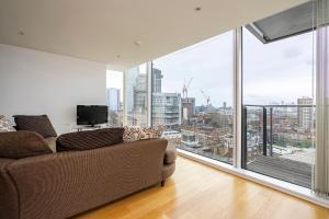 a living room with a couch and a large window at Borough Flat with City Views by UnderTheDoormat in London