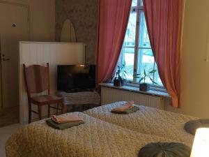 een slaapkamer met 2 bedden, een tv en een raam bij Nostalginen residenssi Taika in Varkaus