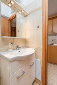 ein weißes Badezimmer mit einem Waschbecken und einem Spiegel in der Unterkunft Lovebirds Nest 1BR Apt. 7' to Acropolis Metro in Athen