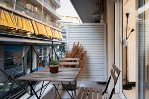 einen Holztisch und Stühle auf dem Balkon in der Unterkunft Lovebirds Nest 1BR Apt. 7' to Acropolis Metro in Athen