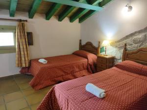 um quarto com 2 camas e lençóis vermelhos em Alojamientos El Castillo em El Berrueco