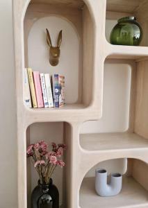 een boekenplank met een vaas met bloemen en een konijn bij Gezellig appartement in Vilvoorde in Vilvoorde