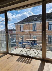 een raam met een tafel en stoelen op een balkon bij Gezellig appartement in Vilvoorde in Vilvoorde