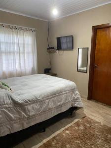 - une chambre avec un lit et une télévision murale dans l'établissement Ranchinho Santa Luzia, à Campos do Jordão