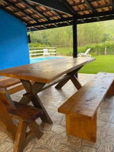 een houten picknicktafel en banken op een patio bij Ranchinho Santa Luzia in Campos do Jordão