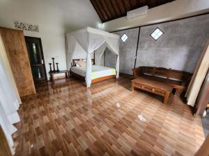 um quarto com uma cama de dossel e piso em madeira em Enchanting Two Bedroom Villa With Private Pool em Ubud