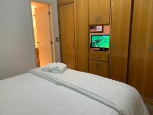 um quarto com uma cama branca e uma televisão em Get a Flat 909 - Conforto Ibirapuera em São Paulo