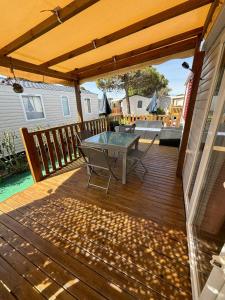 a patio with a table on a wooden deck at Mobil home 6 à 8 personnes Sans Fun Pass in Canet-en-Roussillon