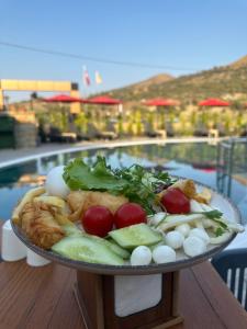 een bord eten op een tafel naast een zwembad bij AGİOS HOTEL in Gokceada Town