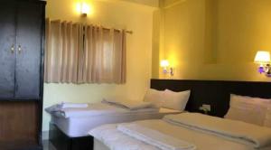 2 Betten in einem Hotelzimmer mit weißer Bettwäsche in der Unterkunft Hotel Suite Inn Lodge in Pokhara