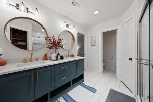 La salle de bains est pourvue d'une coiffeuse bleue et d'un miroir. dans l'établissement Spacious 6 Bed House near Airport, Pet-Friendly, Close to AFB, à San Antonio