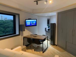 a living room with a table and a tv on the wall at Get a Flat - 703 Luxo e Conforto - Ibirapuera in São Paulo