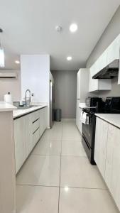a large white kitchen with a sink and a stove at Stylish Condo In Tribeca in San Pedro Sula