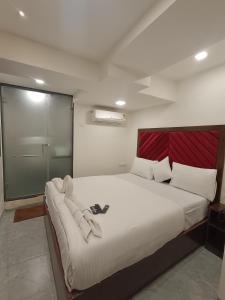 a bedroom with a large white bed with a red headboard at AR Residency in Mumbai