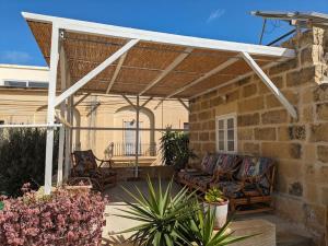 eine Terrasse mit einer weißen Pergola, Stühlen und Pflanzen in der Unterkunft PERLA 21 in Żebbuġ