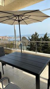 una mesa de madera con una sombrilla en el balcón en Black Sea Apartment, en Nesebar