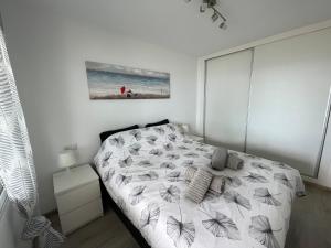 ein weißes Schlafzimmer mit einem Bett und einem Gemälde an der Wand in der Unterkunft Altea Beach Apartment in Altea