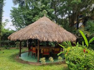 une cabane avec des chaises et un toit de paille dans l'établissement Foyer du Marin, à Douala