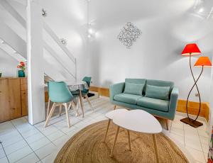 ein Wohnzimmer mit einem Sofa, Stühlen und einem Tisch in der Unterkunft Porte du Vignoble Séjour à Libourne in Libourne
