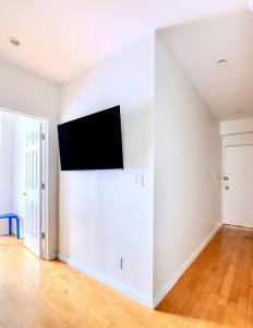 an empty living room with a flat screen tv on the wall at Stylish and Cozy 2BD apartment in New York