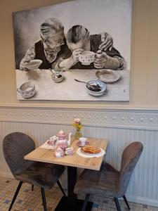 a painting of two people drinking tea at a table at Au Coeur d'Alle in Alle