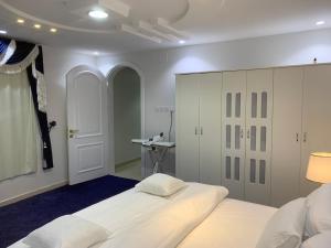 1 dormitorio con 1 cama blanca grande y escritorio en شاليه en Rusibah