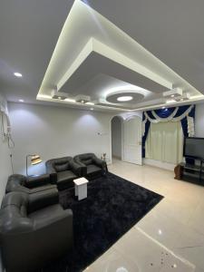 uma sala de estar com sofás pretos e uma televisão em شاليه em Rusibah