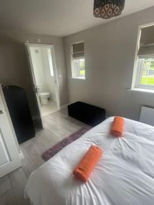 a bedroom with a bed with two orange pillows on it at Lovely 2 Bed, detached home. in Seacroft