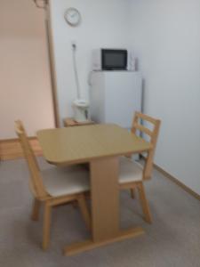 a wooden table with two chairs and a refrigerator at Naoshima Accommodation Menjuku Ura - Vacation STAY 25585v in Naoshima