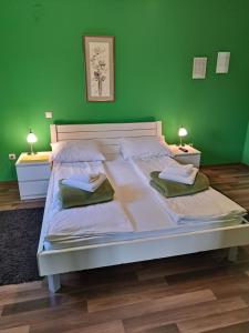 a bedroom with a large white bed with green walls at Rooms Modrušan in Slunj
