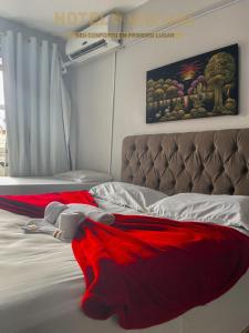 um quarto com uma cama com um cobertor vermelho em Hotel Novo Gama em Novo Gama