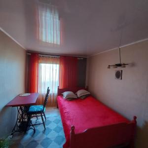 a small bedroom with a red bed and a table at Tuka Talu Soomaa piirkonnas in Tori