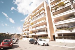 a parking lot with cars parked in front of a building at Borghetto Vara by BuddyRent in Rome