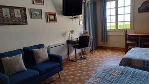 um quarto de hotel com um sofá azul e uma televisão em Le relais du phare em Gatteville-le-Phare