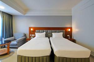 a hotel room with two beds and a chair at Palette - Madhapur in Hyderabad