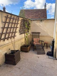 um pátio com um banco, uma cadeira e uma planta em Maisonnette de plain-pied plein cœur du perche em Igé