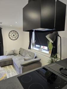 a living room with a couch and a clock on the wall at Ole Butt Cottage in Cinderford