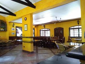 un restaurante con mesas, sillas y paredes amarillas en Chácara Santa Rita en São Pedro