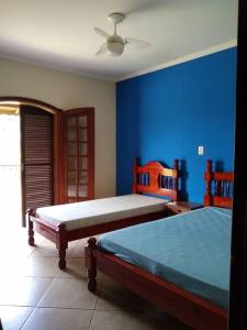 1 dormitorio con 2 camas y pared azul en Chácara Santa Rita en São Pedro
