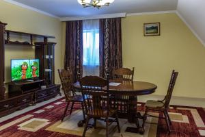une salle à manger avec une table et une télévision dans l'établissement Гранд Алексік, à Trouskavets