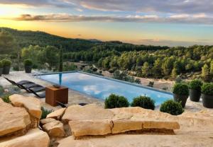 uma piscina no meio de uma montanha com árvores em Luxurious secluded villa em Calaceite