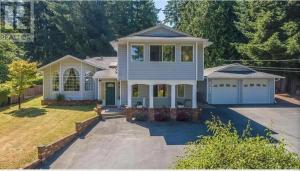 a white house with a porch and a driveway at Beautiful home with one acre land for leisure time in Vancouver Island in Nanaimo