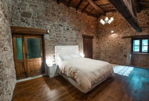 um quarto com uma cama e uma parede de pedra em Os Queixeiros Rural House em Chantada