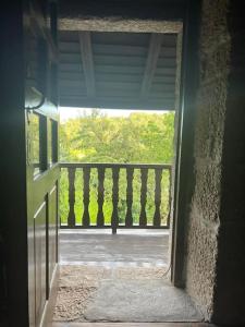 uma porta aberta para uma varanda com vista em Os Queixeiros Rural House em Chantada