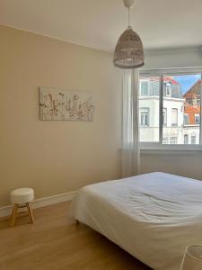 een slaapkamer met een wit bed en een raam bij Appartement "Escapade à Malo"pour 4 à 6 personnes 5 mn de la plage in Duinkerke