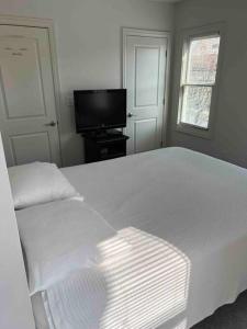 - une chambre blanche avec un lit et une télévision à écran plat dans l'établissement Luxury Short North Home! Newly Renovated/Private, à Columbus