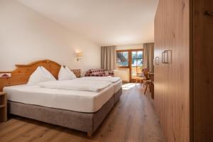 ein Hotelzimmer mit einem großen Bett und einem Schreibtisch in der Unterkunft Hotel am Sonnenhügel in Filzmoos